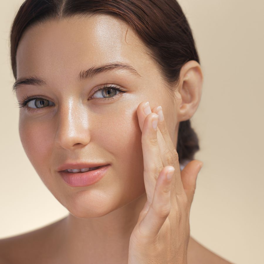Mujer joven aplic&aacute;ndose rutina facial